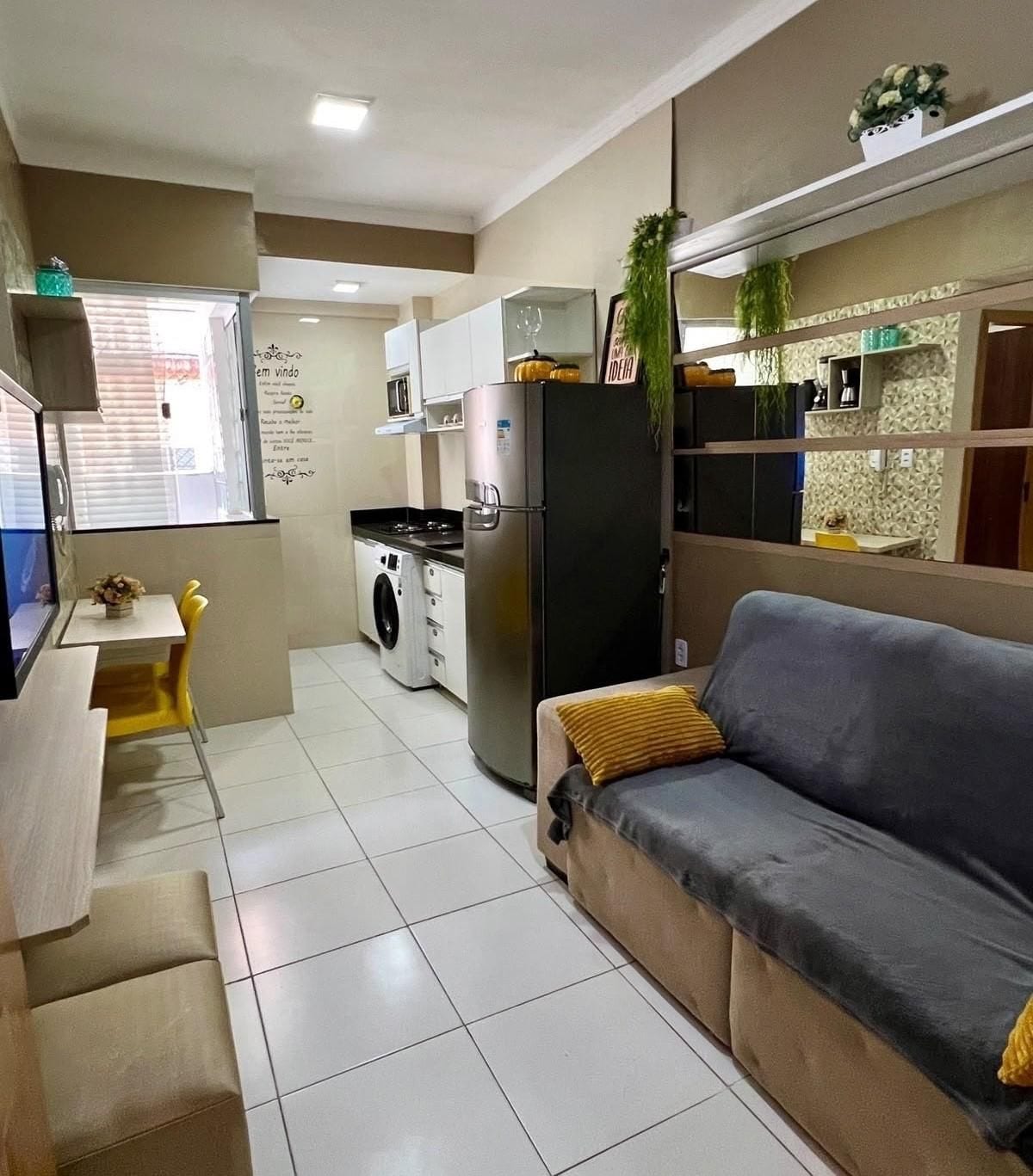 A compact living space with a sofa, a washing machine, a refrigerator, and a dining area.