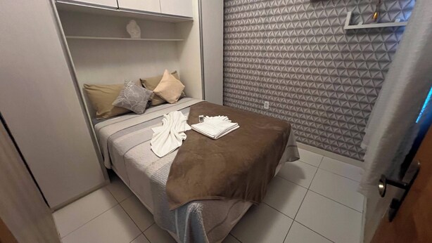 Ein Hotelzimmer mit einem Bett, Kissen, einer braunen Decke und einem gefalteten weißen Handtuch.