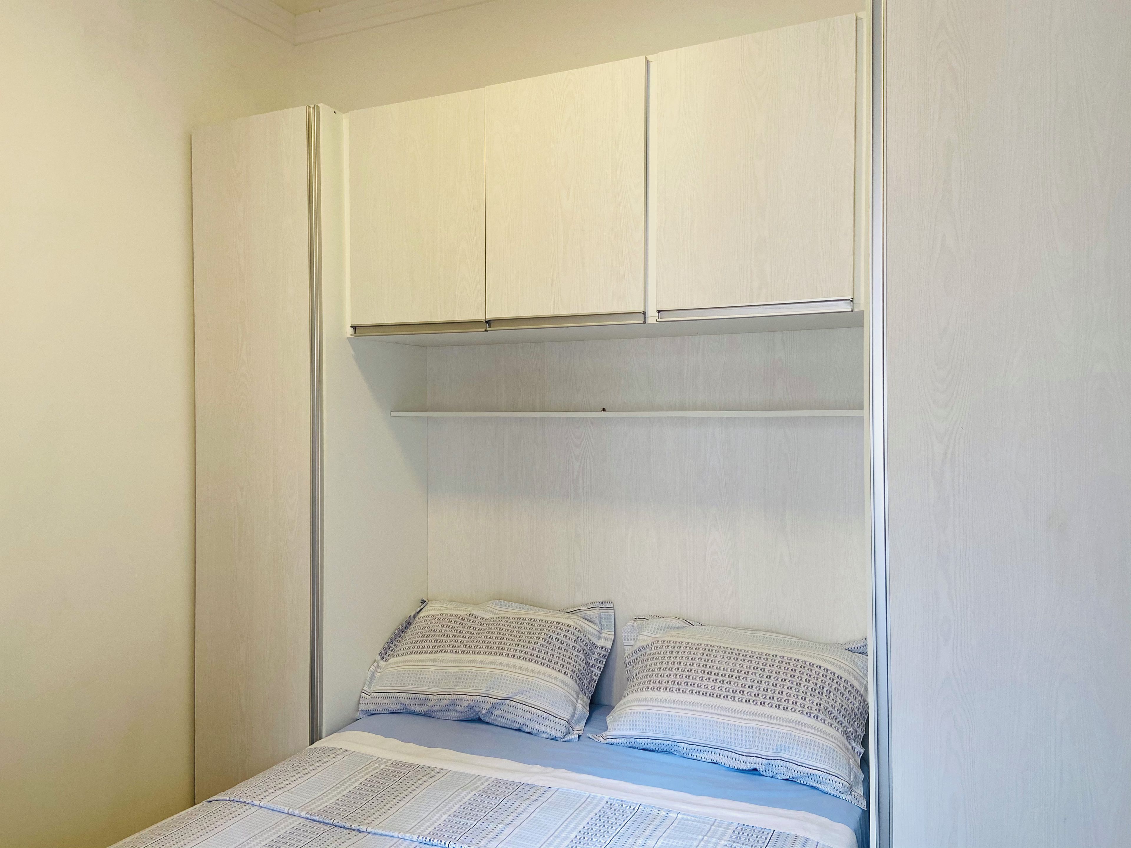 A bedroom with a bed, pillows, and a wardrobe.