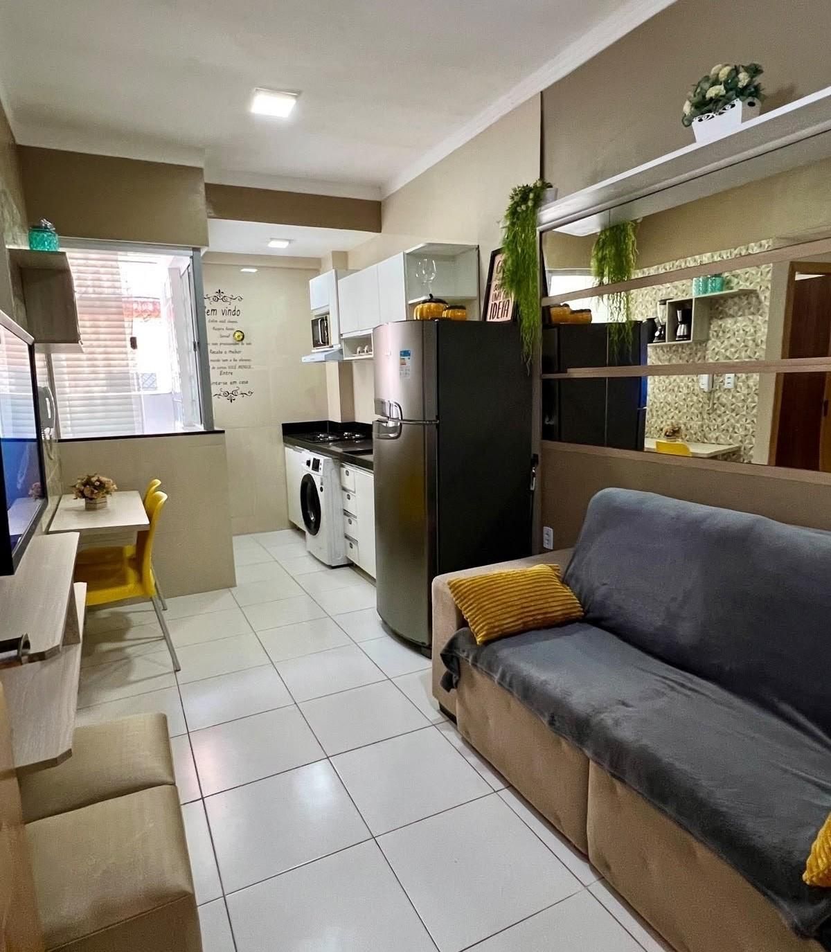 Un espacio habitable compacto con kitchenette, un sofá, comedor y lavadora.