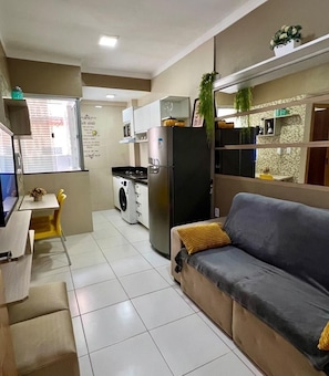 A compact living space with a kitchenette, a sofa, a dining area, and a washing machine. - 104 Apartamento lindo e delicado (Belém)