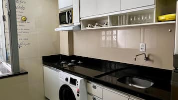 Una cocina compacta con lavadora, microondas y pileta.