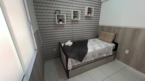 Ein kleines, modernes Schlafzimmer mit einem Bett, einem Nachttisch und einem an der Wand befestigten Regal mit einer Pflanze.