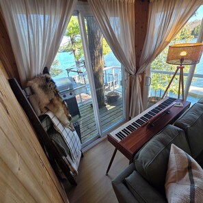 A room with a view of a lake, a grill outside, and a keyboard on a couch. - Lil' Bears' Lair (Arnstein)