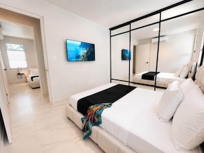 A modern bedroom with a large bed, a mirror, and a painting on the wall. - Casita Olivo {} A place to feel at home π‘β¨ (Guaynabo)