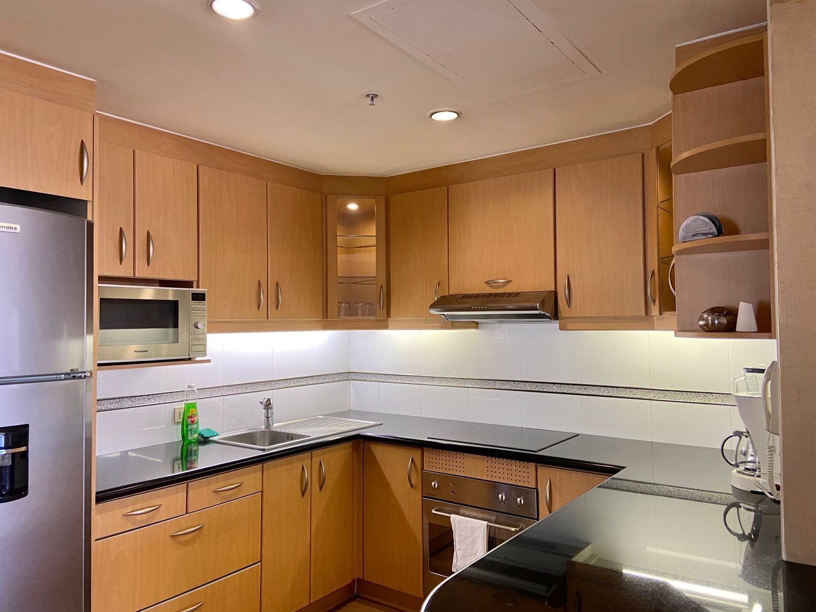 A modern kitchen with wooden cabinets, stainless steel appliances, and a black countertop.