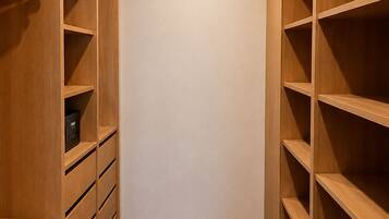 A walk-in closet with wooden shelving and drawers, a white wall, and a wooden floor.