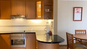 A compact kitchen with built-in appliances, a dining area with a table and chairs, and a framed picture on the wall.