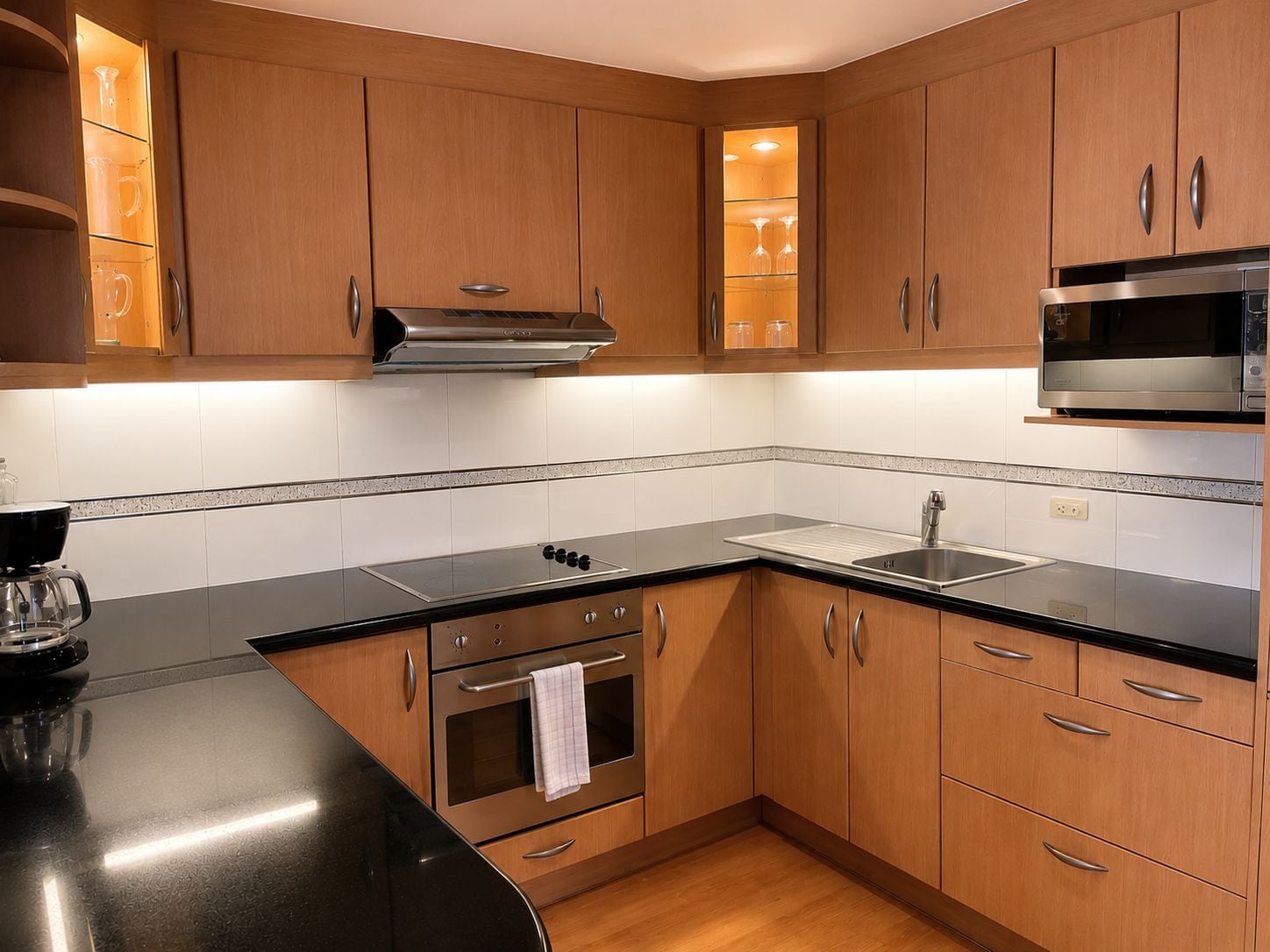 Una cocina moderna con armarios de madera, un microondas de acero inoxidable y una encimera negra.