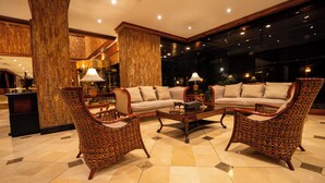 Un amplio hall con un gran sofá, dos sillones, una mesa de centro y una lámpara decorativa.