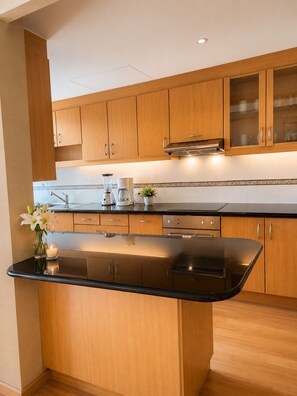 Una cocina moderna con armarios de madera, encimera negra y estufa integrada.