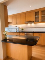 Una cocina moderna con armarios de madera, encimera negra y estufa integrada.