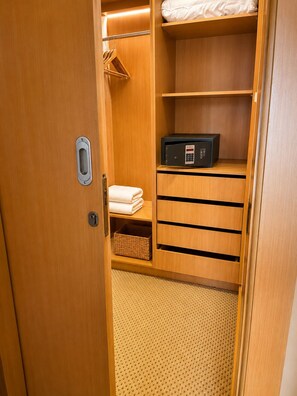 Un armario de madera con estantes, una barra para colgar ropa y un microondas.
