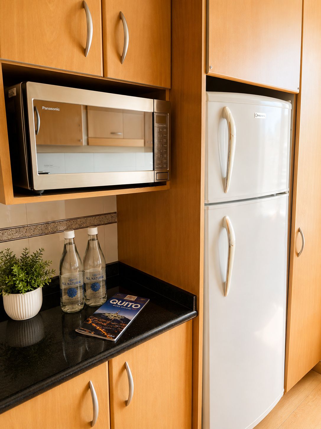 Una cocina con microondas, refrigerador y una revista sobre la encimera.