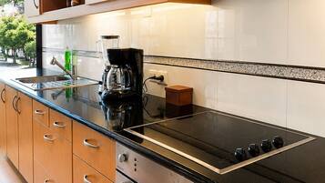 A modern kitchen with wooden cabinets, a black countertop, a stainless steel stove, and a coffee maker.