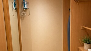 Un armario espacioso con puertas de madera, una percha y una planta pequeña sobre un tocador de madera.