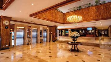 Un vestíbulo espacioso con techo alto, un candelabro y una mesa de recepción.