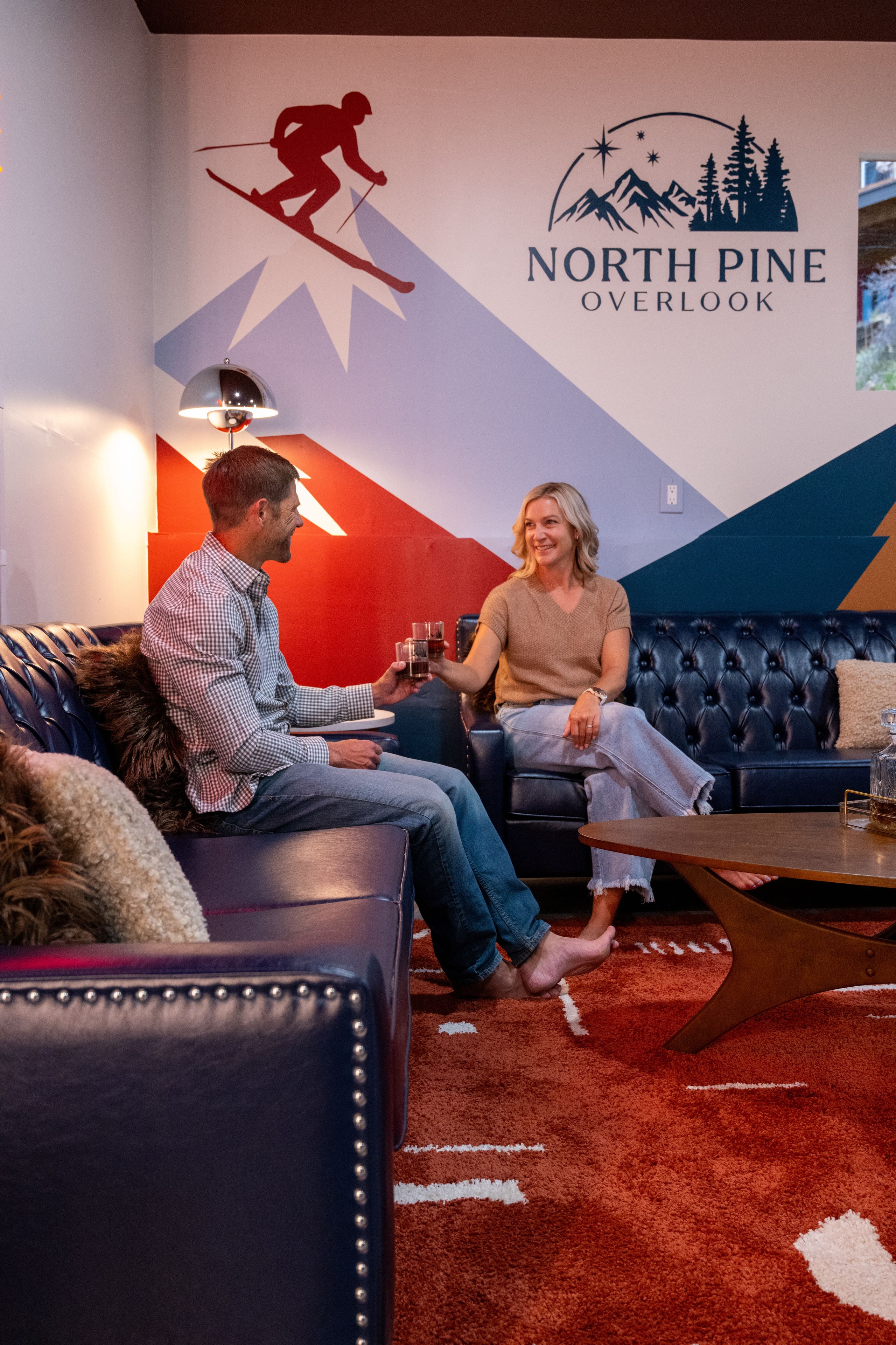 A room with a logo for North Pine Overlook, a couch, a coffee table, and a lamp.