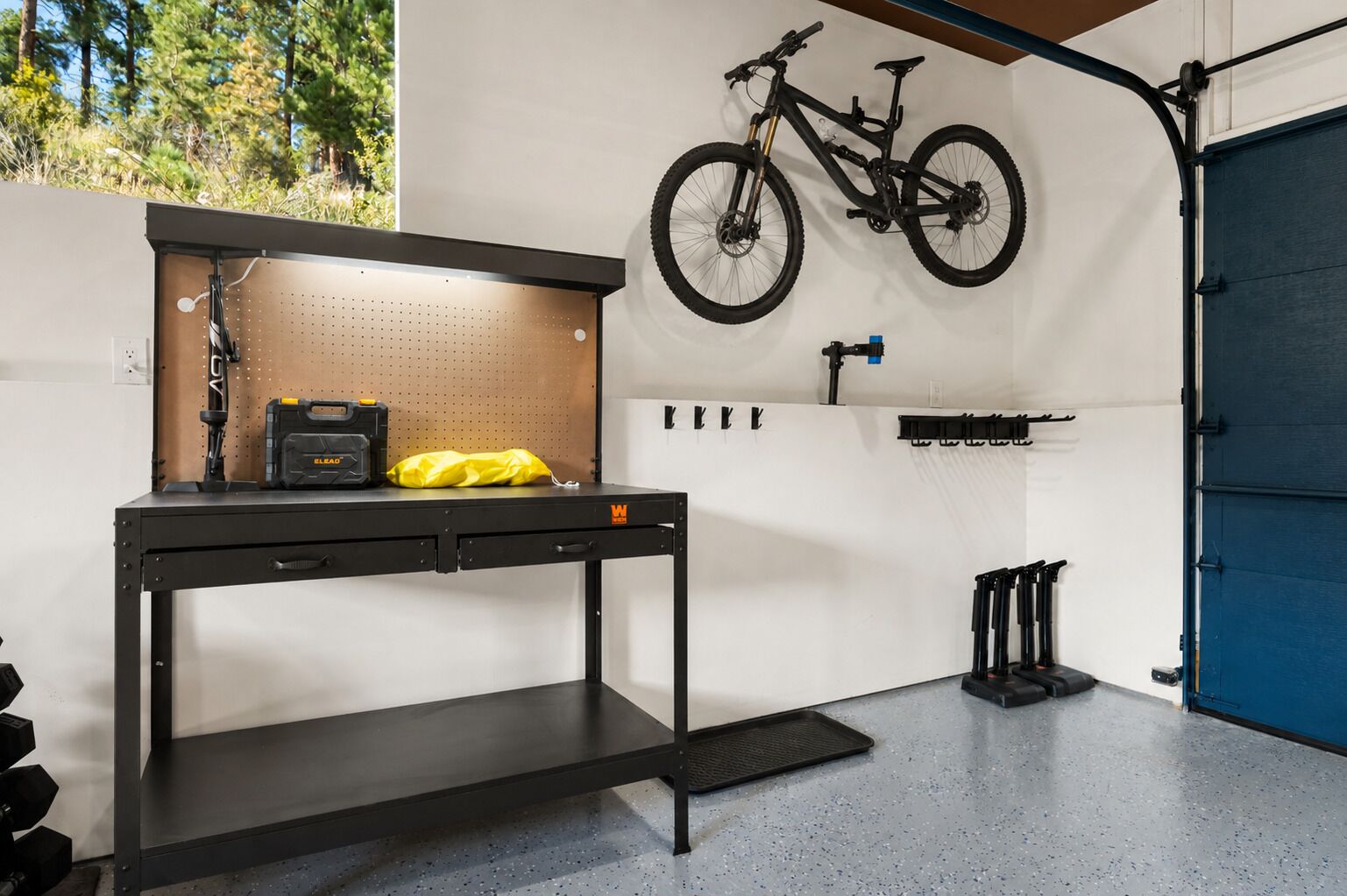 Een werkruimte met een prikbord, een werkbank en een fiets erboven.