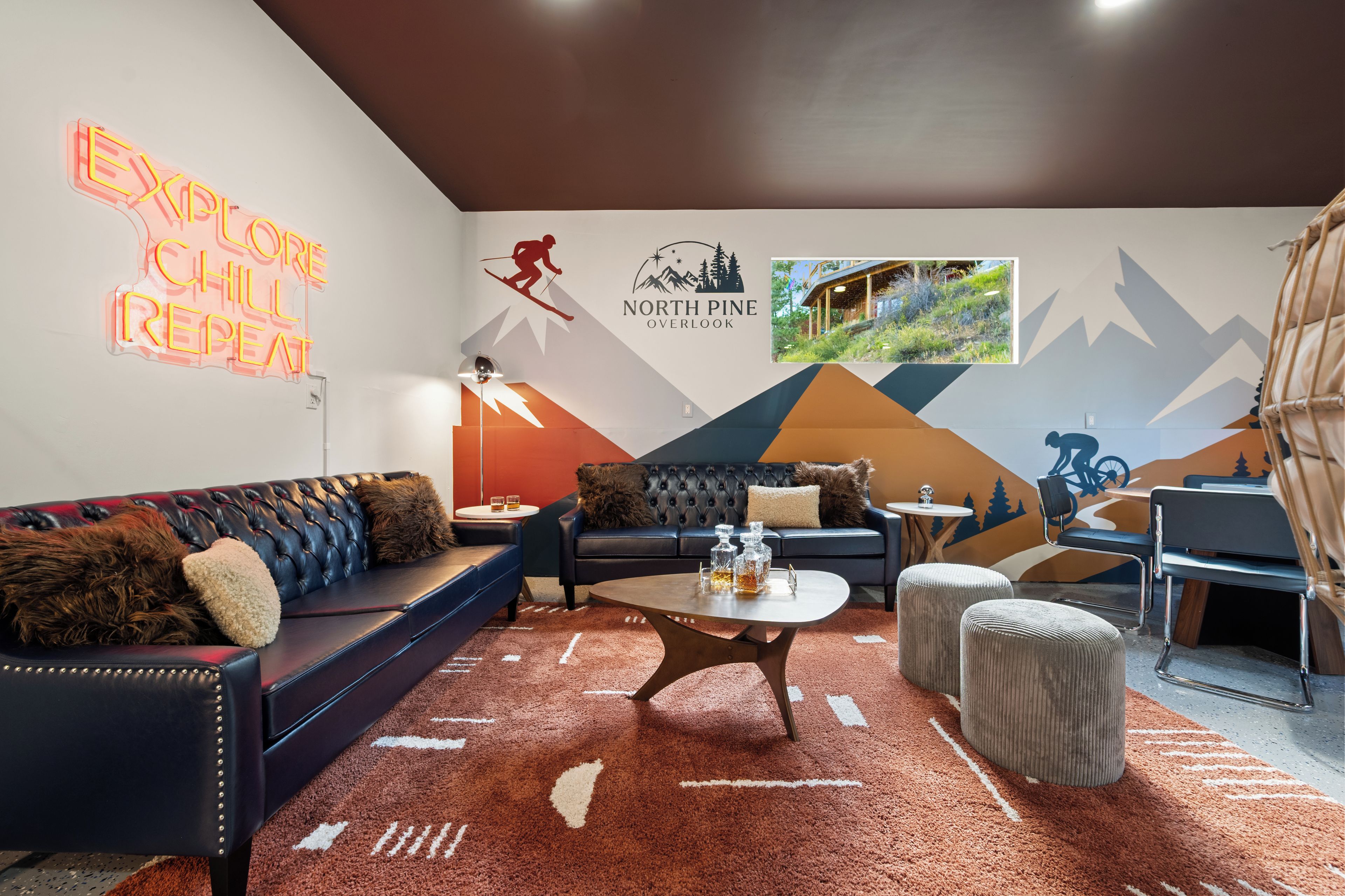 A modern living room with a sofa, coffee table, and ottoman, a neon sign, and a wall mural.