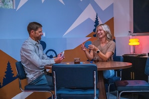 Two people seated at a round table with a blue chair, playing cards.