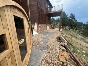 En træbygning med balkon, sten trapper og en grussti.