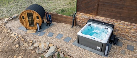A hot tub and a wooden structure with a ladder, surrounded by gravel and rocks.