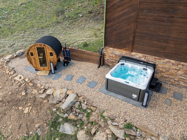 A hot tub and a wooden structure with a ladder, surrounded by gravel and rocks.