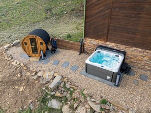 Un jacuzzi y una estructura de madera con escalera, rodeado de grava y rocas.