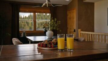 A wooden table with two glasses of orange juice and a plate of strawberries and muffins.