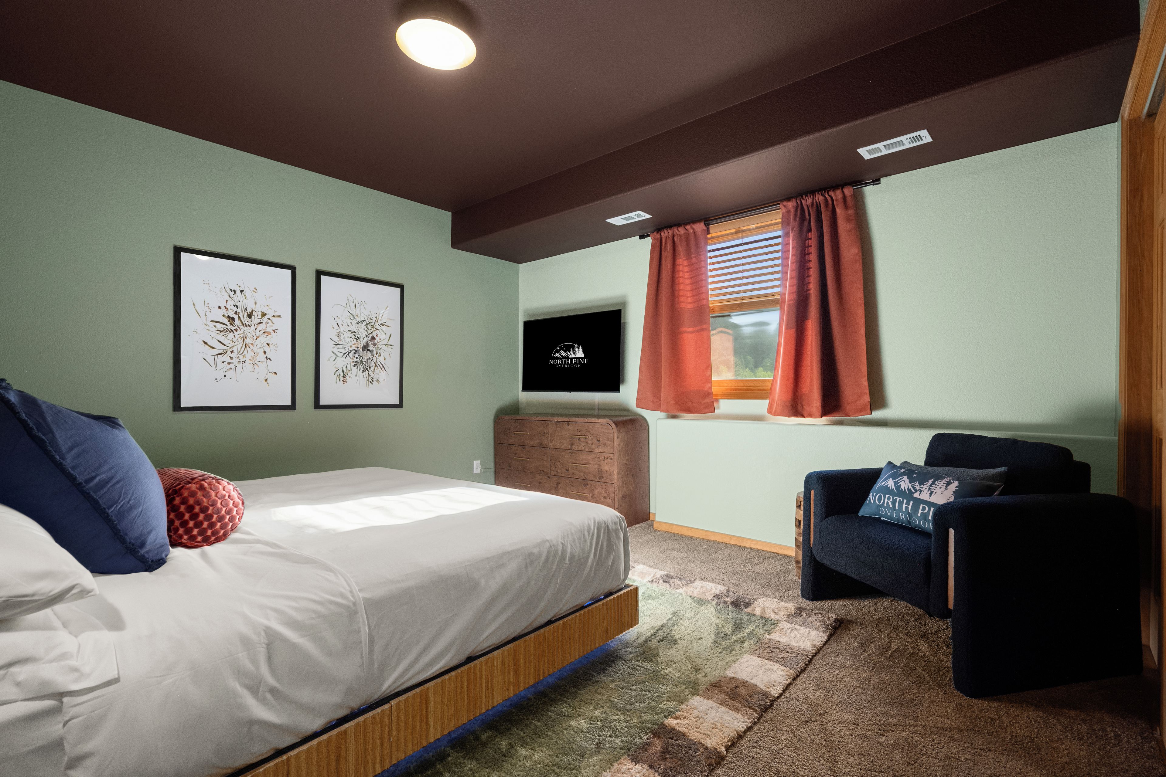 Una camera da letto con un letto, una cassettiera, una sedia e due quadri appesi al muro.