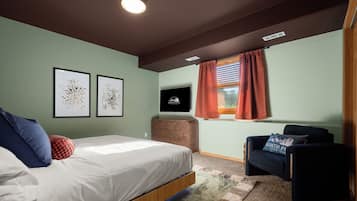 Una camera da letto con un letto, una cassettiera, una sedia e due quadri appesi al muro.