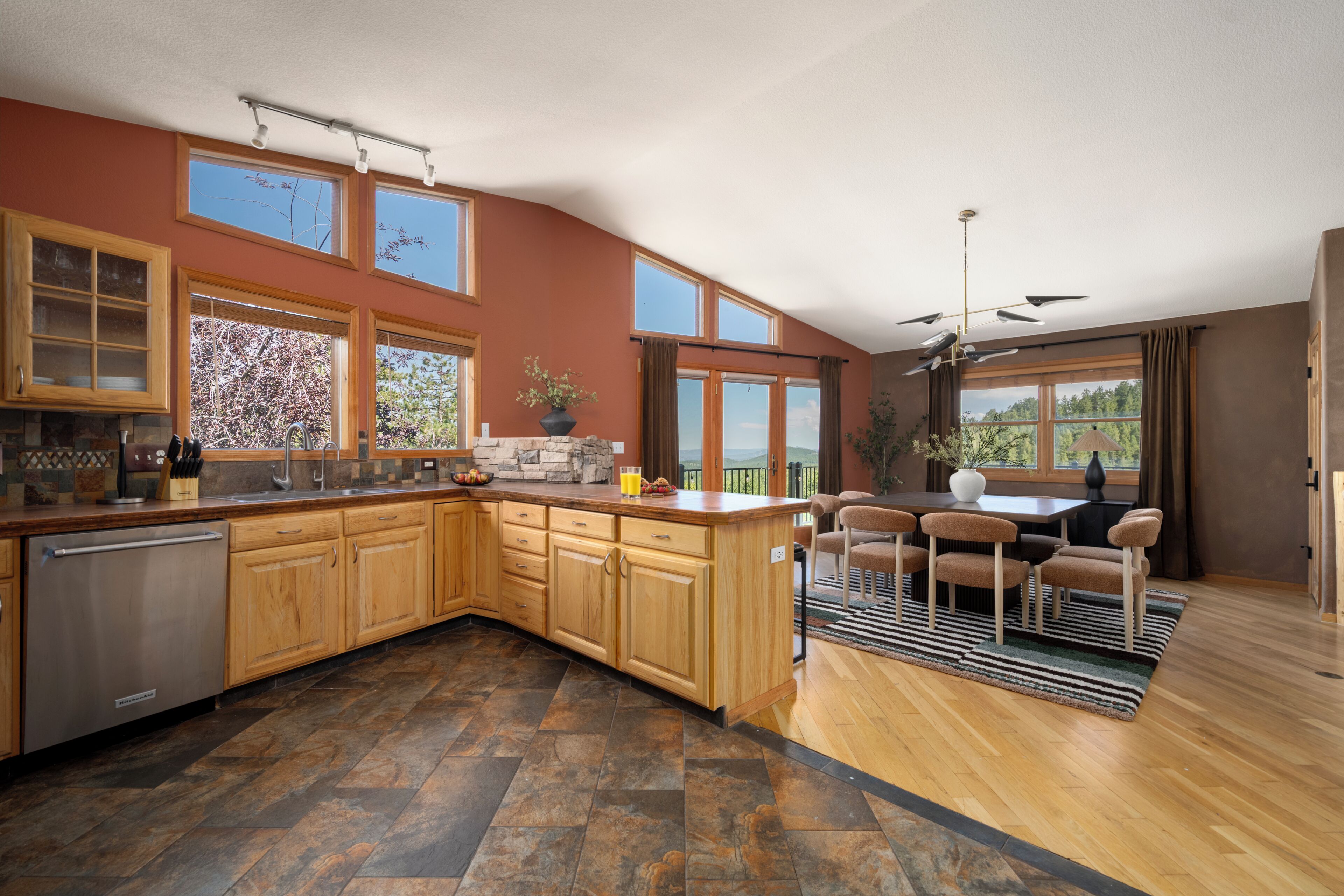 A spacious kitchen with a central island, wooden cabinets, and a stone backsplash.
