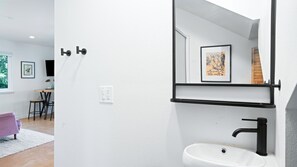 A modern bathroom with a white sink, black faucet, and a mirror with a framed picture.