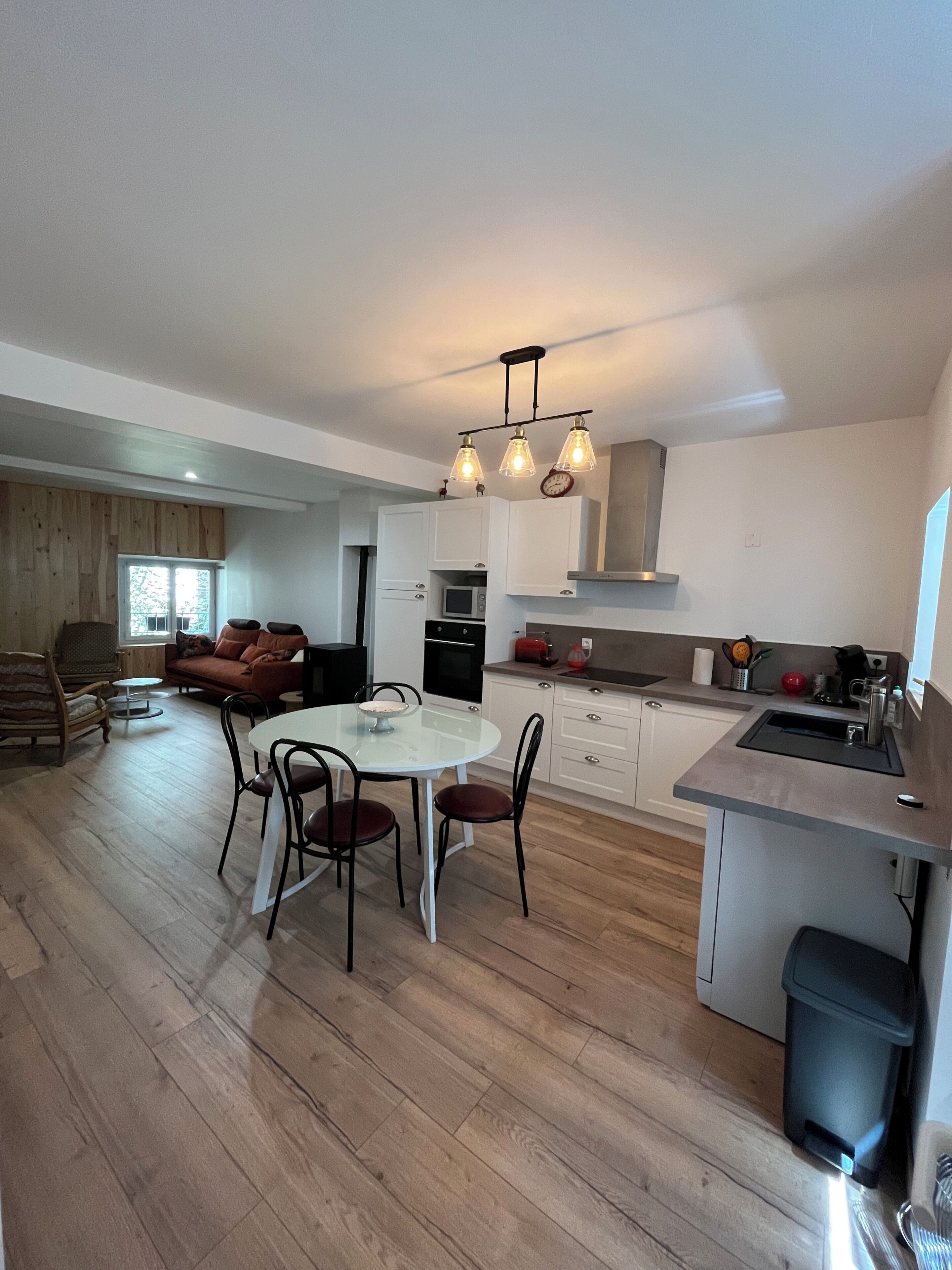 A modern kitchen with a dining area, wooden flooring, and a built-in oven.
