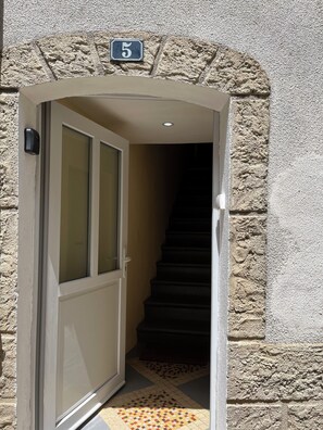Eine Tür mit Hinweisschild, eine Glastür und eine Treppe, die nach innen führt.