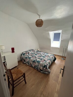 A compact room with a bed, a chair, a desk, a lamp, a window, and a ceiling fan. - Le Cazal Vacation Rental (Saint Geniez d'Olt et d'Aubrac)