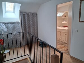 Een kamer met een trap, een douchegedeelte en uitzicht op een keuken.
