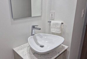 Une salle de bain avec un lavabo blanc, un miroir et un porte-serviettes.