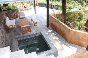 Un área de patio exterior con un jacuzzi, escalones de piedra y mobiliario de madera.