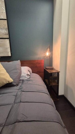 Ein Schlafzimmer mit einem Bett, einem Nachttisch und einer Wandlampe.