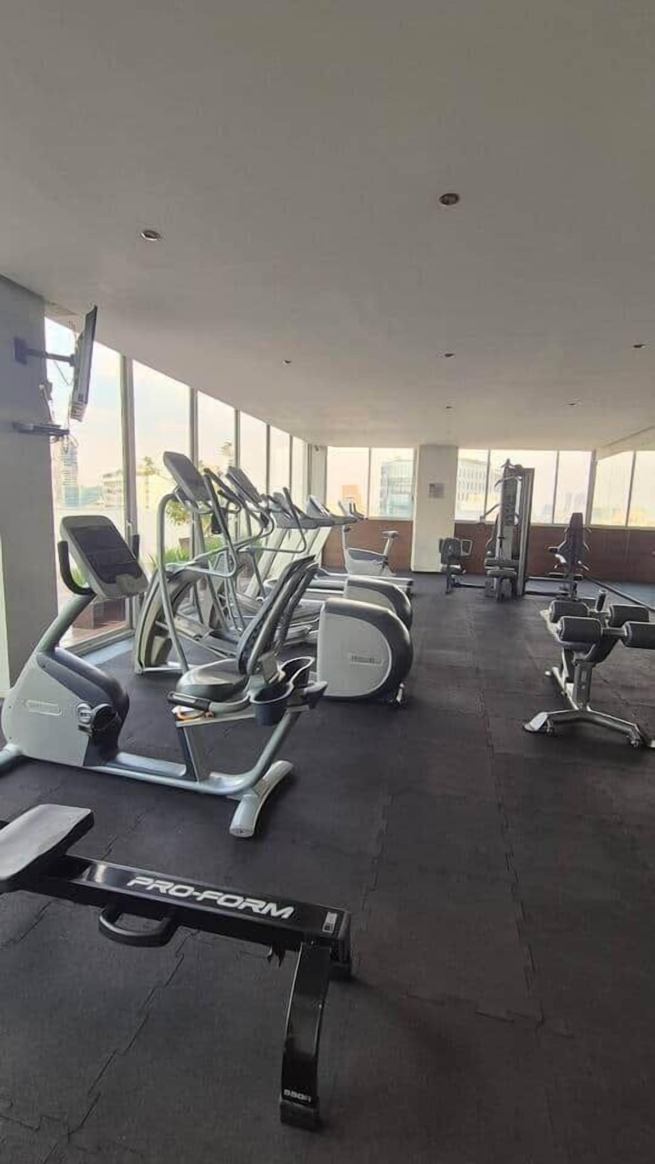 Une salle de sport équipée de tapis de course, de vélos elliptiques et d'appareils de musculation.