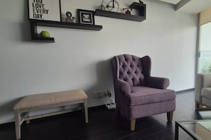 Ein modernes Wohnzimmer mit einem gesteppten Sessel, einer Bank und dekorativen Wandregalen.