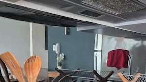 Keittiössä on musta työtaso, puiset keittiövälineet säilytysastiassa ja ruostumattomasta teräksestä valmistettu liesituuletin.