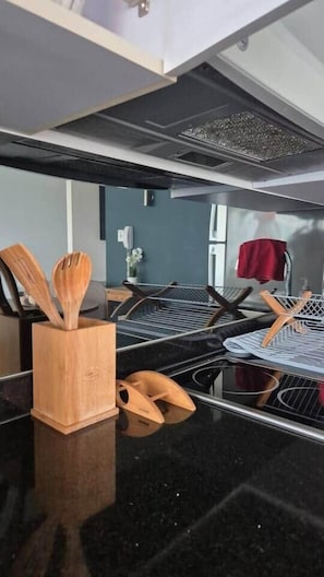 Eine Küche mit schwarzem Arbeitsplatz, Holzkochlöffeln in einer Halterung und einer Edelstahl-Dunstabzugshaube.