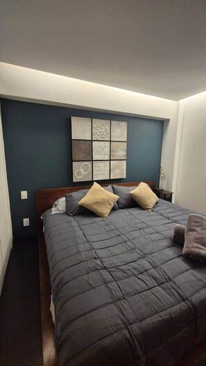 A bedroom with a bed, two pillows, a wall art piece, and a bedside table. - Paulina Schnaider cdmx san isidro (Mexico City)
