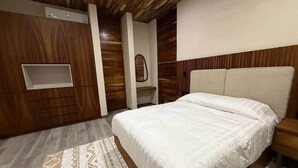 A bedroom with a bed, a nightstand, a mirror, and a built-in shelf. - Deisy TownHouse Oaxaca (San Pedro Mixtepec)