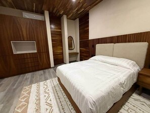 Ein Schlafzimmer mit einem Bett, einem Nachttisch, einem Spiegel und einer fest eingebauten Ablage.
