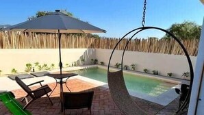 A patio area with a hanging swing chair, a pool, and a table with chairs. - Deisy TownHouse Oaxaca (San Pedro Mixtepec)