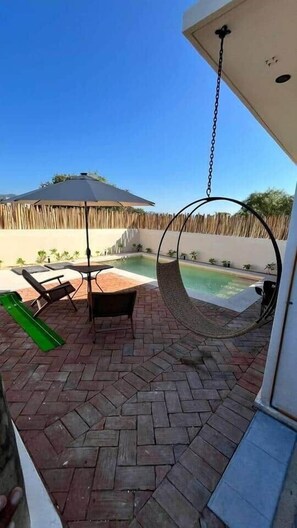 Eine Terrasse mit einer Hängematte, einem Pool und einem Tisch mit Stühlen.